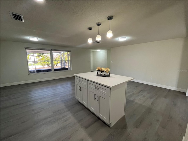 kitchen with a textured ceiling, hanging light fixtures, white cabinetry, and dark wood-type flooring