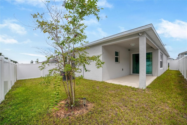 back of house with a lawn and a patio