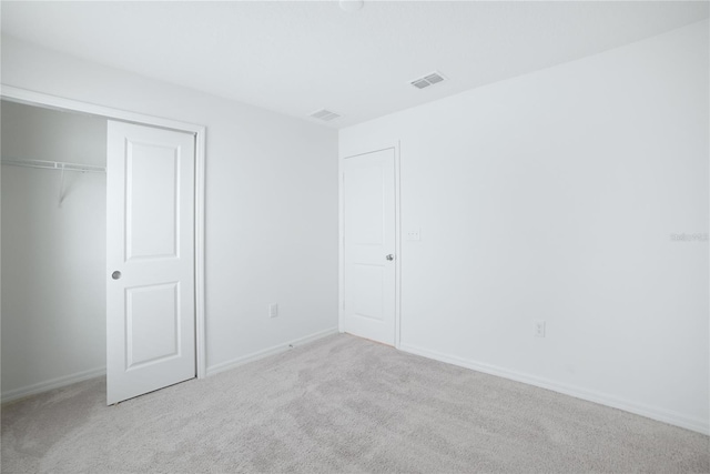 unfurnished bedroom with light carpet and a closet