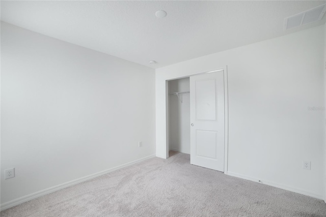 unfurnished bedroom featuring light carpet and a closet