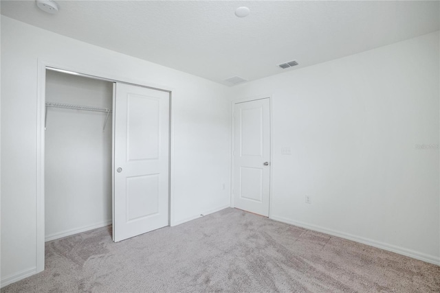 unfurnished bedroom with a closet and light colored carpet