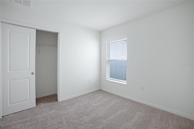 unfurnished bedroom with light carpet and a closet