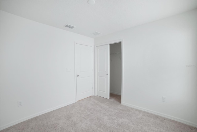 unfurnished bedroom featuring a closet and light colored carpet