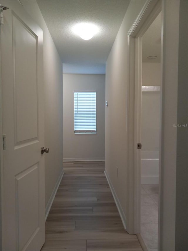 corridor featuring a textured ceiling and dark hardwood / wood-style flooring