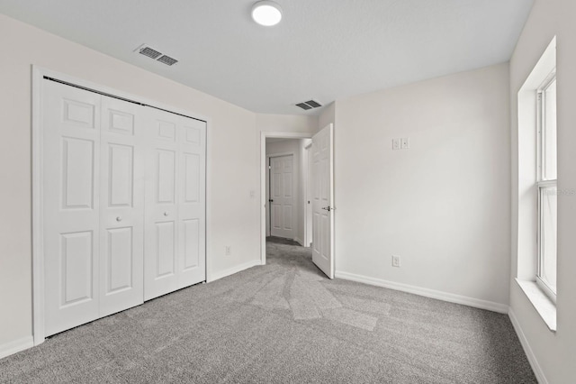 unfurnished bedroom featuring light carpet and a closet