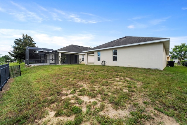 rear view of property featuring a yard and glass enclosure