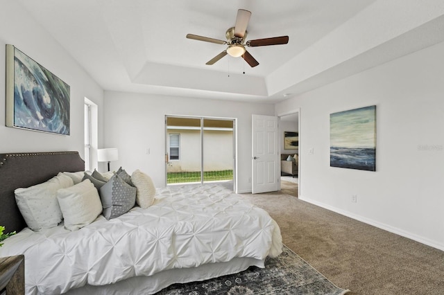 carpeted bedroom featuring a raised ceiling and ceiling fan