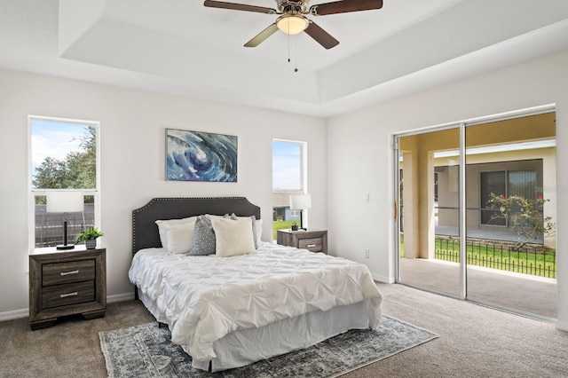 bedroom featuring a raised ceiling, access to exterior, ceiling fan, and multiple windows