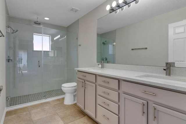 bathroom featuring tile patterned floors, vanity, toilet, and a shower with shower door