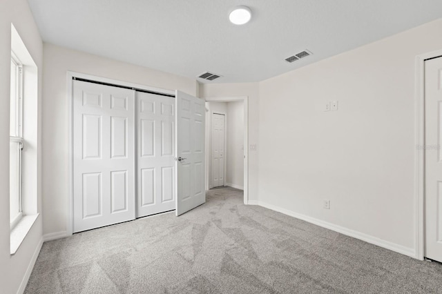 unfurnished bedroom featuring light carpet and a closet