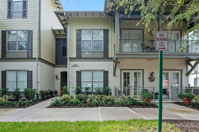 townhome / multi-family property with a balcony, french doors, and covered porch