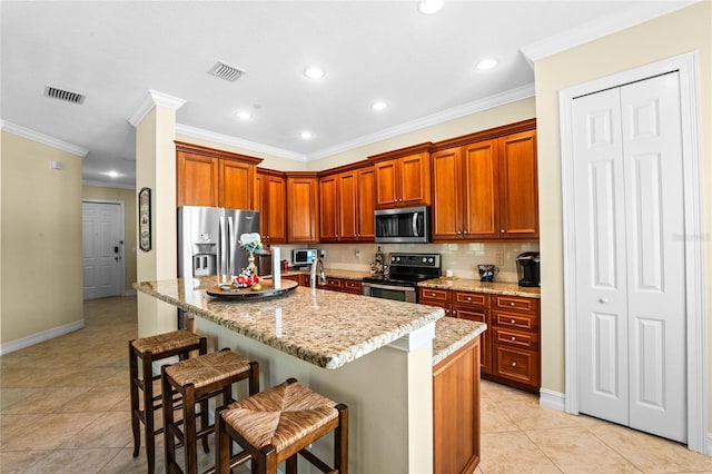 kitchen with a breakfast bar area, light tile patterned floors, an island with sink, stainless steel appliances, and light stone counters