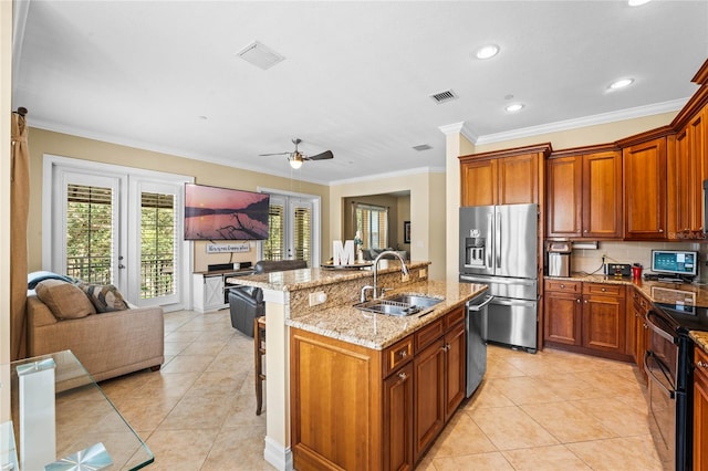 kitchen featuring a kitchen bar, sink, ceiling fan, appliances with stainless steel finishes, and a center island with sink