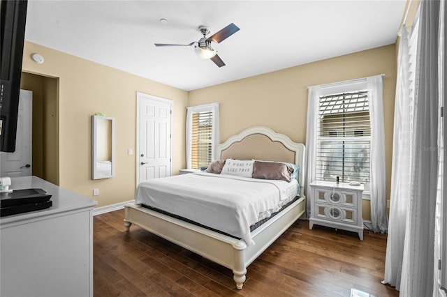 bedroom with ceiling fan, dark wood-type flooring, and baseboards