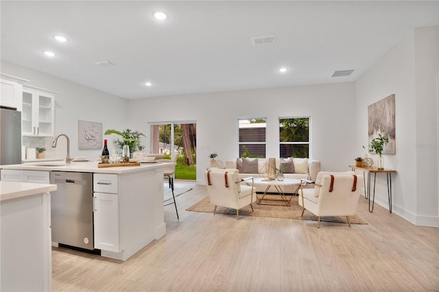 kitchen with appliances with stainless steel finishes, light hardwood / wood-style floors, a breakfast bar, sink, and white cabinetry