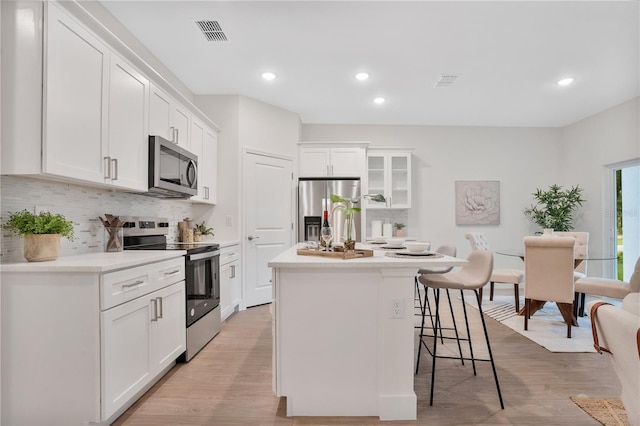 kitchen with white cabinetry, stainless steel appliances, and a center island with sink