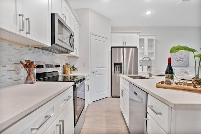 kitchen with light hardwood / wood-style flooring, backsplash, stainless steel appliances, sink, and white cabinets