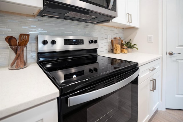 kitchen with light hardwood / wood-style flooring, backsplash, appliances with stainless steel finishes, and white cabinetry