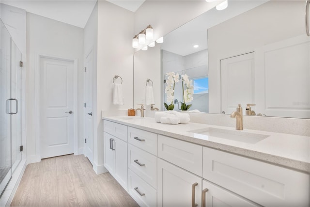 bathroom with hardwood / wood-style floors, a shower with door, and vanity