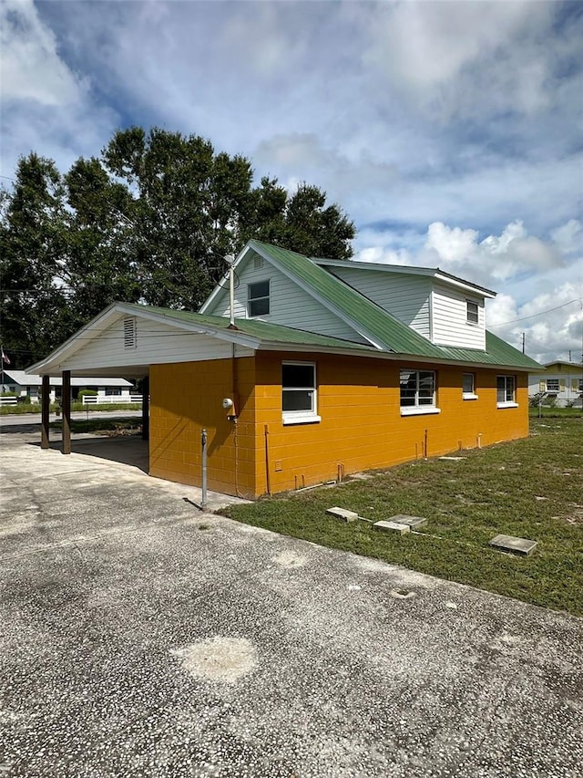 view of property exterior with a lawn and a carport