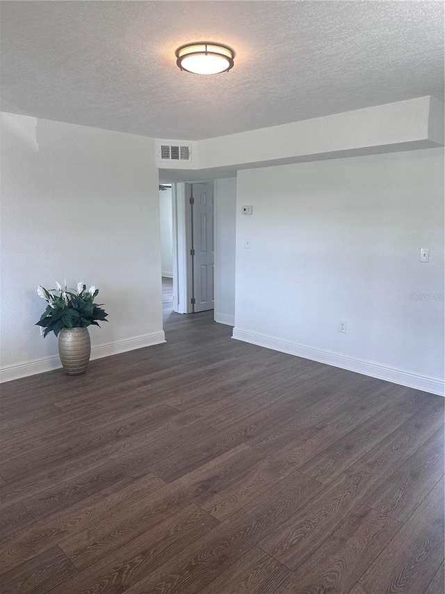 spare room with a textured ceiling and dark hardwood / wood-style floors