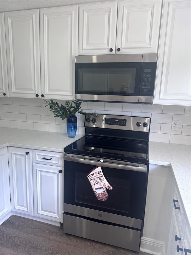 kitchen with backsplash, stainless steel appliances, light stone counters, dark hardwood / wood-style floors, and white cabinets