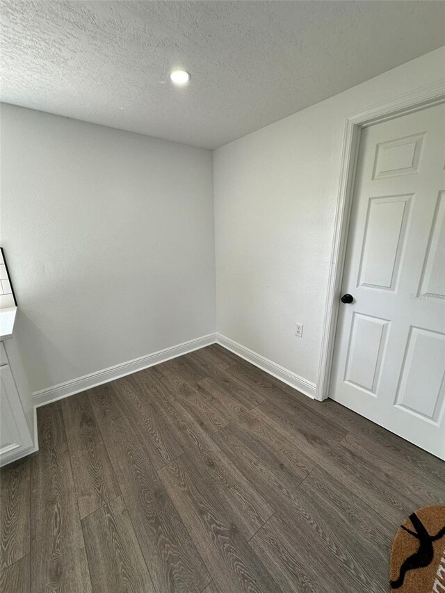 spare room featuring dark hardwood / wood-style flooring and a textured ceiling