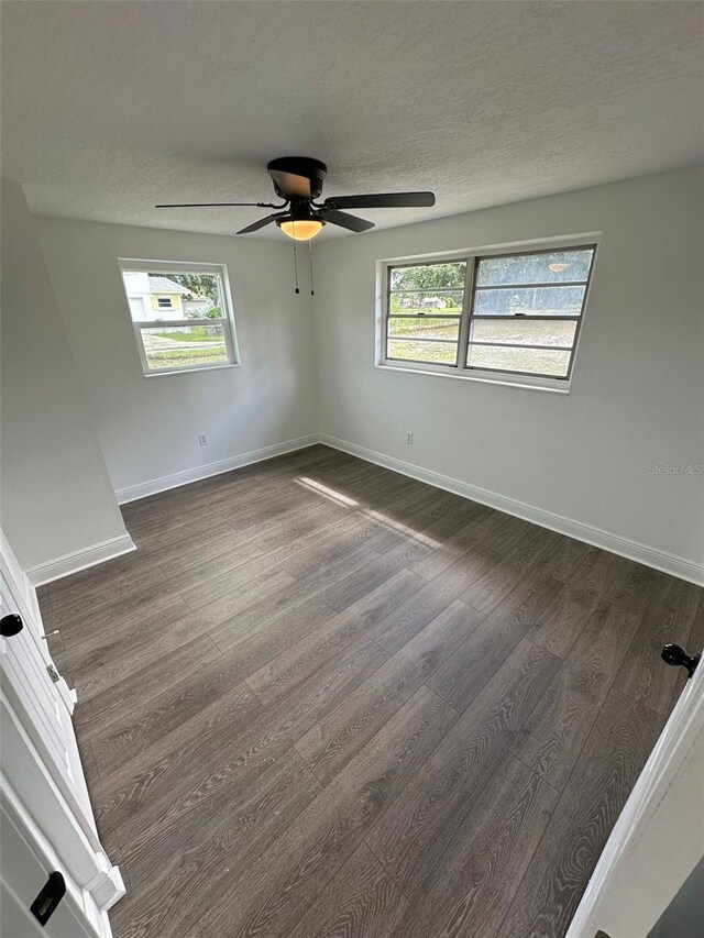 unfurnished room featuring ceiling fan, plenty of natural light, and dark hardwood / wood-style flooring