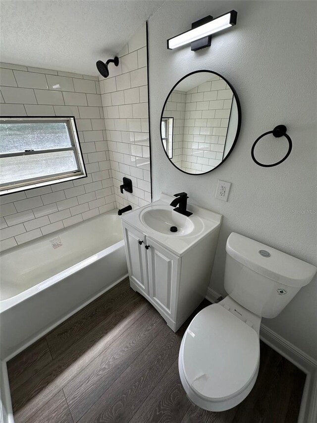 full bathroom with tiled shower / bath, hardwood / wood-style floors, toilet, vanity, and a textured ceiling