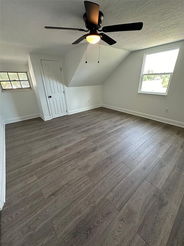 additional living space featuring dark hardwood / wood-style flooring, a wealth of natural light, ceiling fan, and a textured ceiling