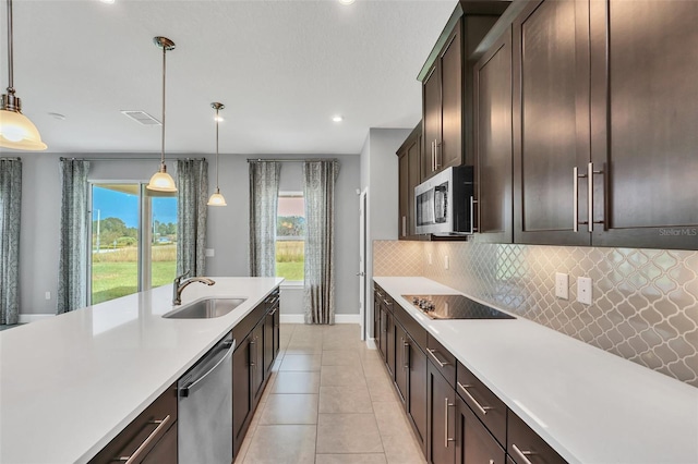 kitchen featuring hanging light fixtures, stainless steel appliances, sink, dark brown cabinetry, and tasteful backsplash