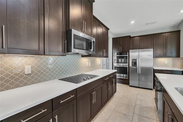 kitchen featuring dark brown cabinetry, stainless steel appliances, tasteful backsplash, and light tile patterned flooring