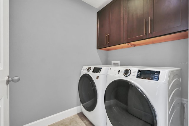 washroom with cabinets, washer and dryer, and light tile patterned floors