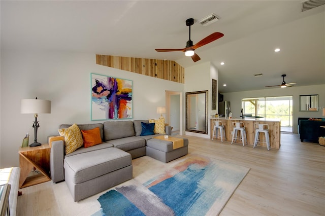 living room featuring ceiling fan, high vaulted ceiling, and light hardwood / wood-style floors