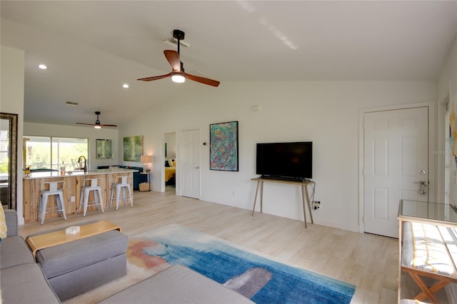 living room featuring light wood-type flooring, ceiling fan, lofted ceiling, and sink