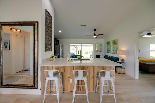 kitchen with ceiling fan, a kitchen breakfast bar, kitchen peninsula, and sink