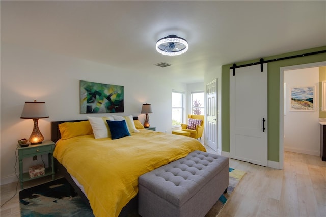 bedroom with a barn door and light wood-type flooring