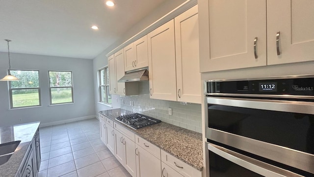 kitchen with tasteful backsplash, white cabinetry, stainless steel appliances, light stone counters, and light tile patterned floors