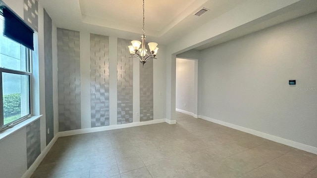 unfurnished room featuring a raised ceiling, a chandelier, and plenty of natural light