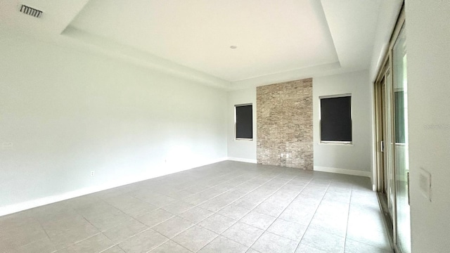 tiled empty room with a tray ceiling