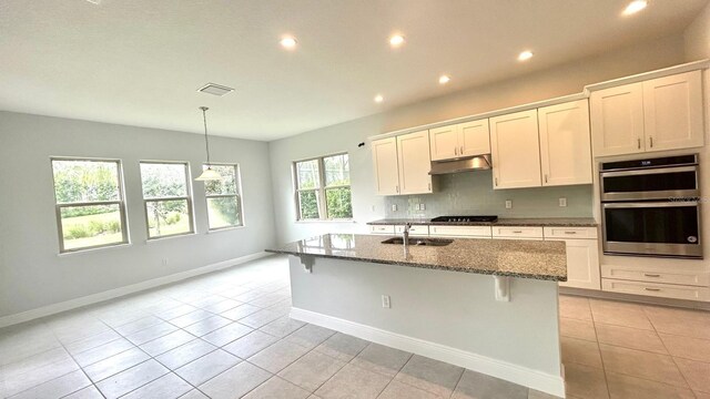 kitchen with a center island with sink, a breakfast bar area, white cabinetry, sink, and stainless steel double oven