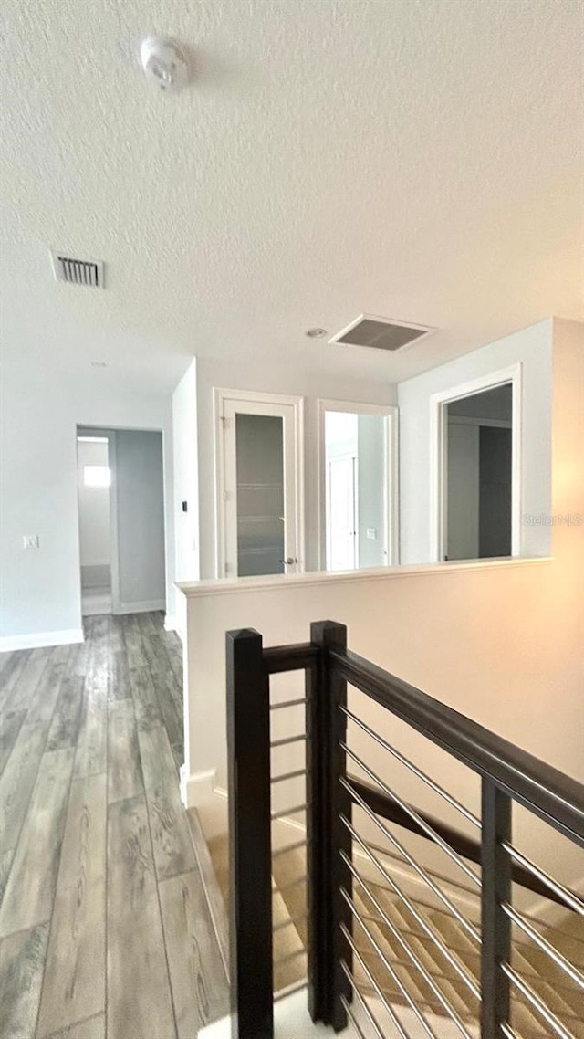 hall featuring a textured ceiling and hardwood / wood-style floors