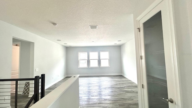 unfurnished room with wood-type flooring and a textured ceiling