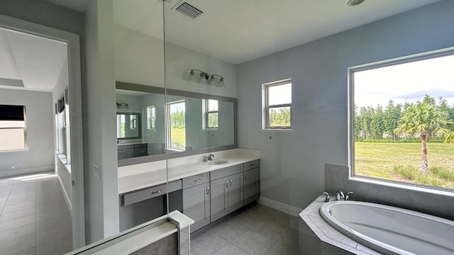 bathroom featuring vanity, tiled tub, and tile patterned flooring