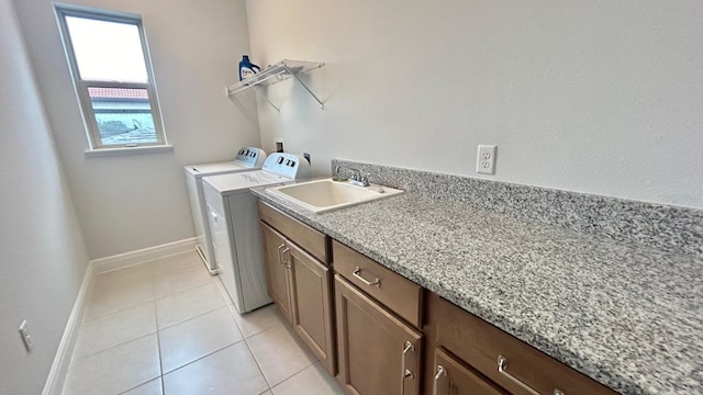 clothes washing area featuring cabinets, sink, separate washer and dryer, and light tile patterned floors