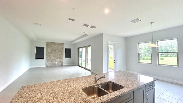 kitchen featuring sink, light stone countertops, decorative light fixtures, and light tile patterned floors