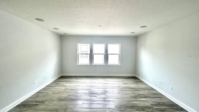 empty room featuring a textured ceiling and dark wood-type flooring