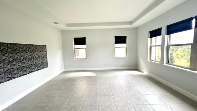 tiled spare room with a tray ceiling