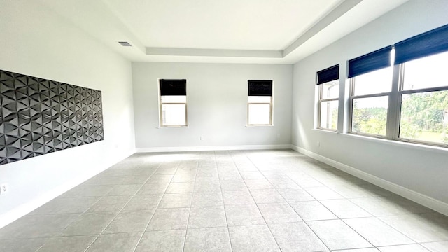 empty room with light tile patterned floors and a raised ceiling