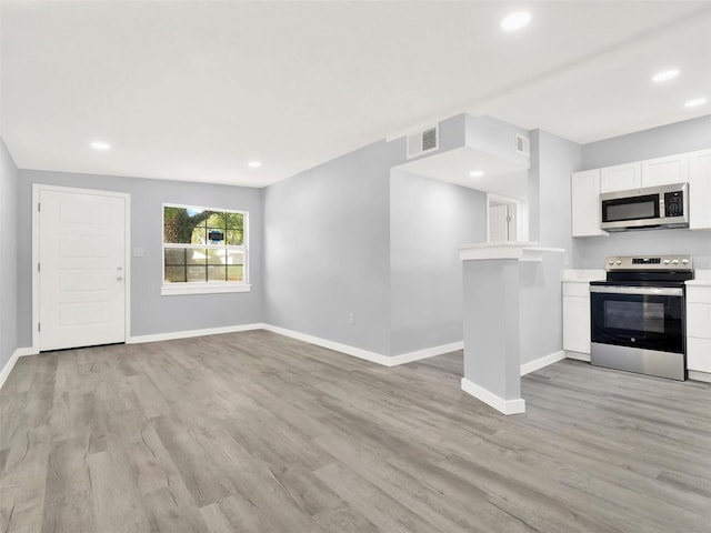 interior space featuring white cabinets, stainless steel appliances, and light hardwood / wood-style floors